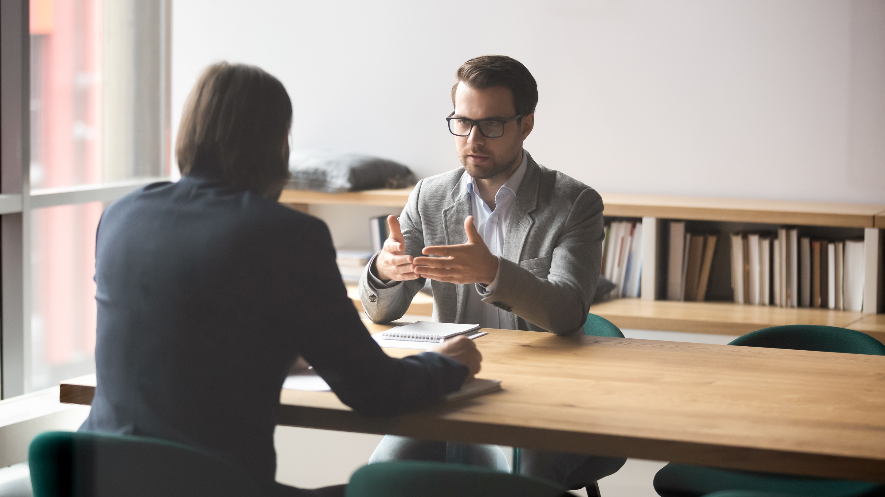 Two people sit at a table to discuss Corporate Conflict Management